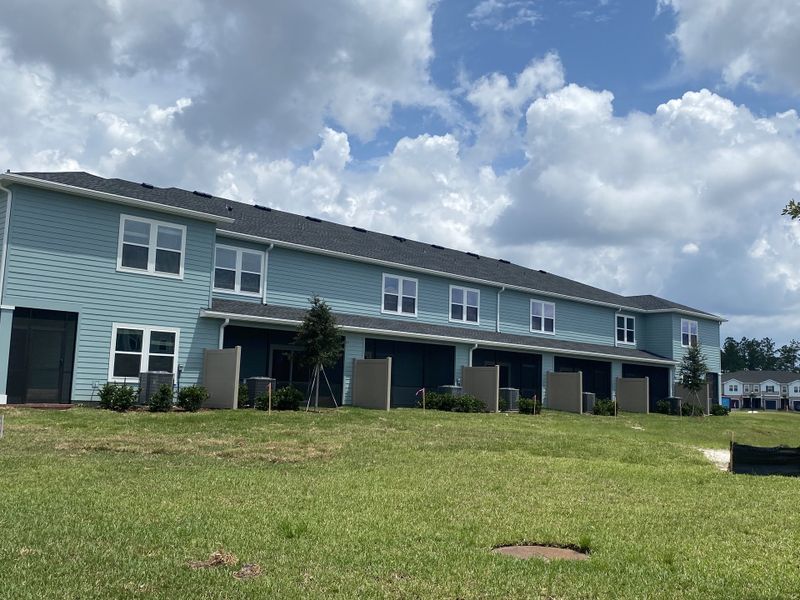 Bright townhomes with pale blue siding and manicured lawns in Shearwater Townhomes by Ryan Homes (St. Augustine, FL).