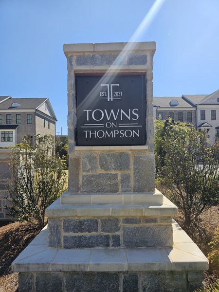 A welcoming entrance sign for Towns on Thompson by The Providence Group in Alpharetta, GA, framed by elegant townhomes.