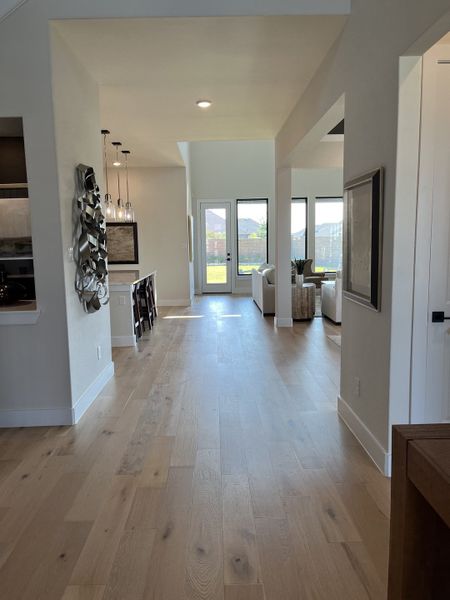 A bright, open-concept living space with wooden floors, modern decor, and abundant natural light through large windows.