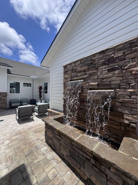 A charming patio with a stone water feature and cozy seating area, perfect for relaxation.