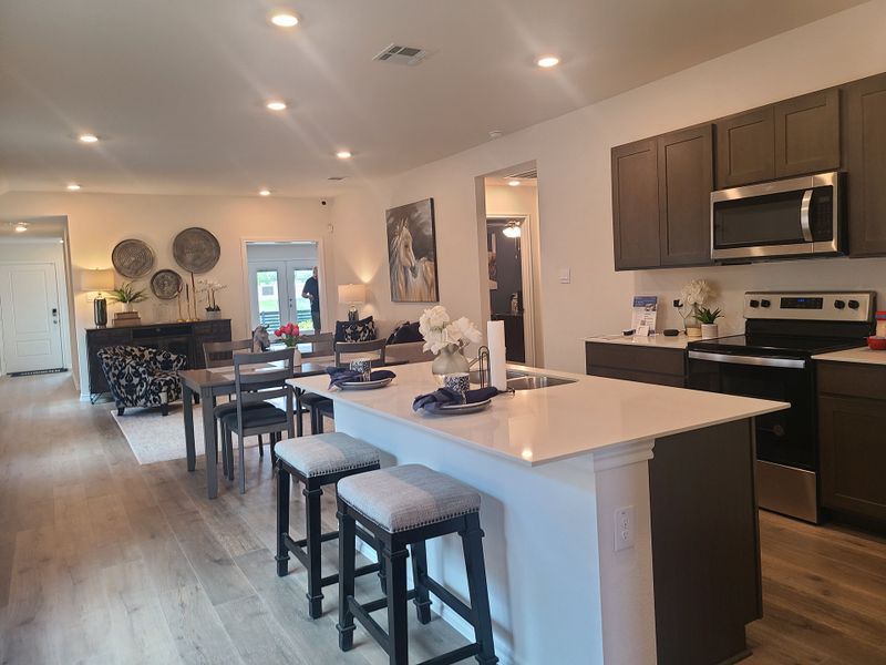 An open-concept kitchen and living area with wood floors, sleek cabinetry, and cozy seating. An open-concept kitchen and living area with wood floors, sleek cabinetry, and cozy seating.