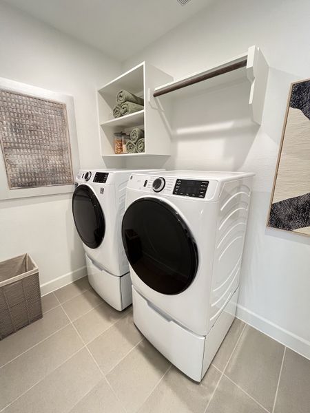 A sleek laundry room featuring modern appliances, open shelving, and stylish decor accents.