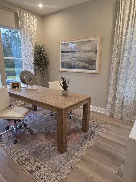 A cozy home office with a wooden desk, elegant rug, neutral tones, and nature-inspired decor. A cozy home office with a wooden desk, elegant rug, neutral tones, and nature-inspired decor.