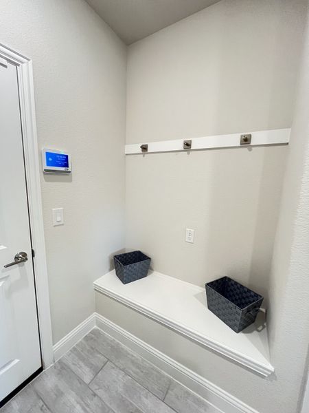 A functional mudroom feature with modern gray tile, storage bench, and coat hooks.