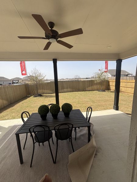 A well-designed outdoor living area with a covered patio, a ceiling fan, and a stylish black dining set. A well-designed outdoor living area with a covered patio, a ceiling fan, and a stylish black dining set.