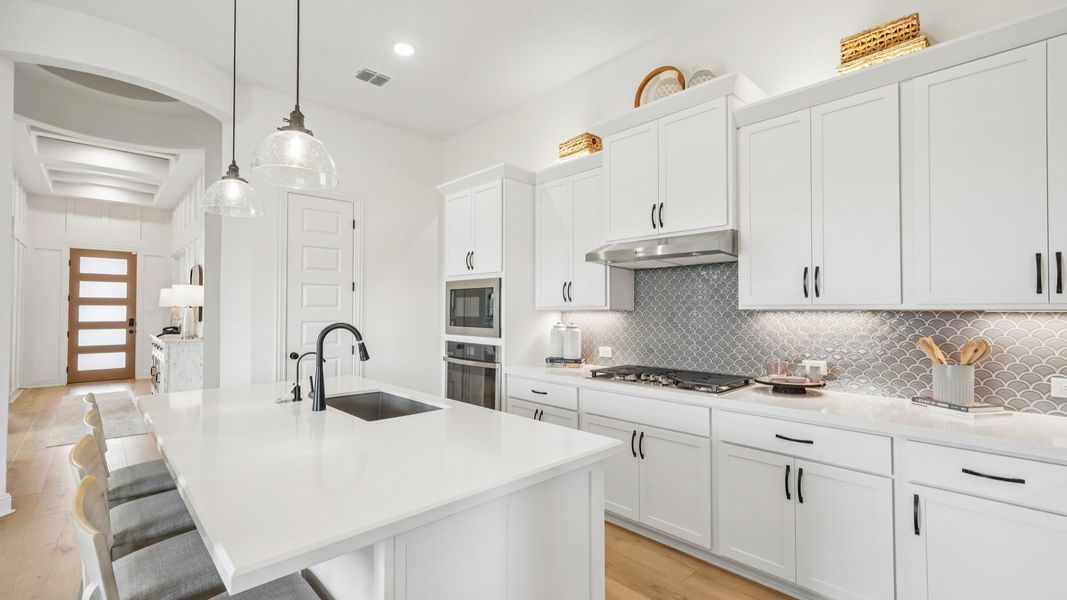 Sleek kitchen design with gas cooktop, vent hood, built-in oven, and modern finishes Sleek kitchen design with gas cooktop, vent hood, built-in oven, and modern finishes