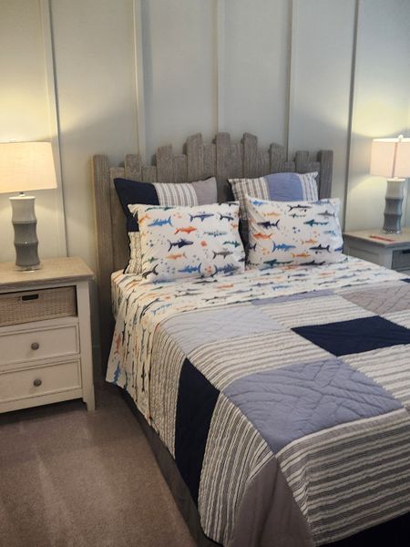 A cozy bedroom with a unique headboard, playful shark-themed bedding, and matching side tables with soft lighting. A cozy bedroom with a unique headboard, playful shark-themed bedding, and matching side tables with soft lighting.