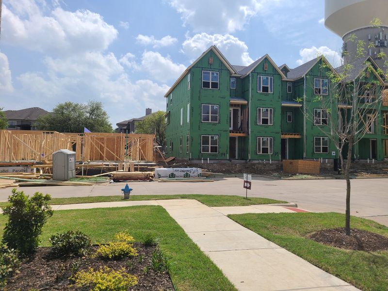 New construction site with green-sheathed townhomes in Wade Settlement by Megatel Homes, Frisco, TX.
