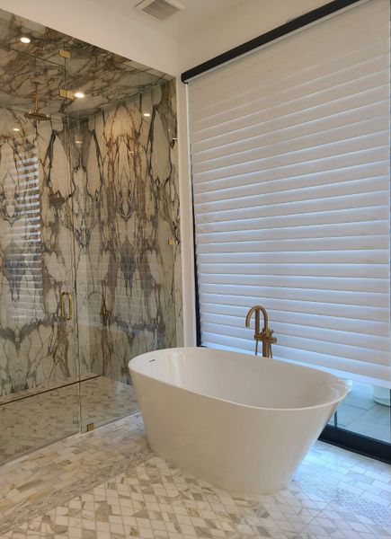A luxurious bathroom features a freestanding tub, gold fixtures, and marble tiles, creating a modern spa-like retreat.