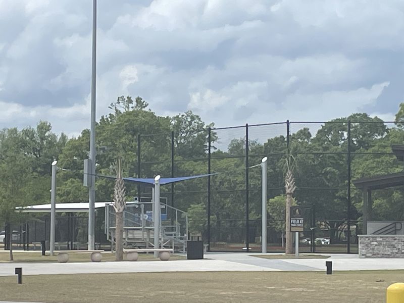 A modern baseball field with lush greenery and seating in Rivers Edge by DRB Homes (North Charleston, SC).