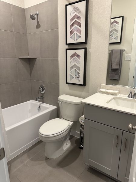 A modern bathroom featuring gray tiles, sleek fixtures, and stylish geometric artwork, creating a serene and elegant space. A modern bathroom featuring gray tiles, sleek fixtures, and stylish geometric artwork, creating a serene and elegant space.
