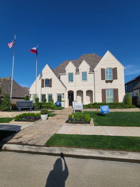 A beautiful white brick home with manicured landscaping in Star Trail: 65ft. lots by Highland Homes (Prosper, TX).