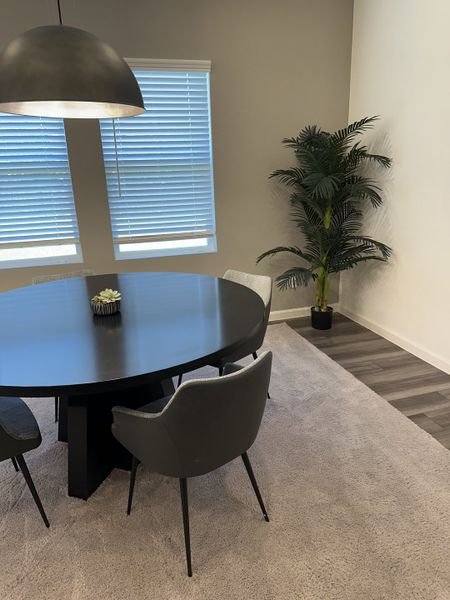 A modern dining room featuring a sleek round table, contemporary chairs, and a stylish pendant light.