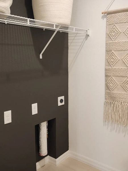 A sleek laundry space with dark accent wall, modern outlets, and cozy woven decor.
