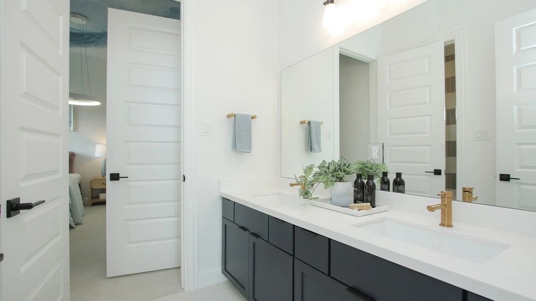 Elegant dual sinks paired with chic gold fixtures and spacious black cabinetry in Coastal Point.