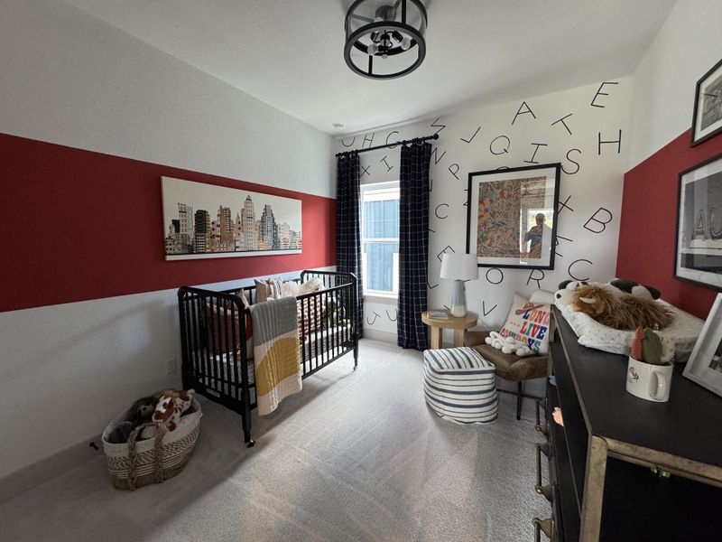 A playful nursery featuring a bold red accent wall, cityscape art, and alphabet decor, complete with a cozy crib.
