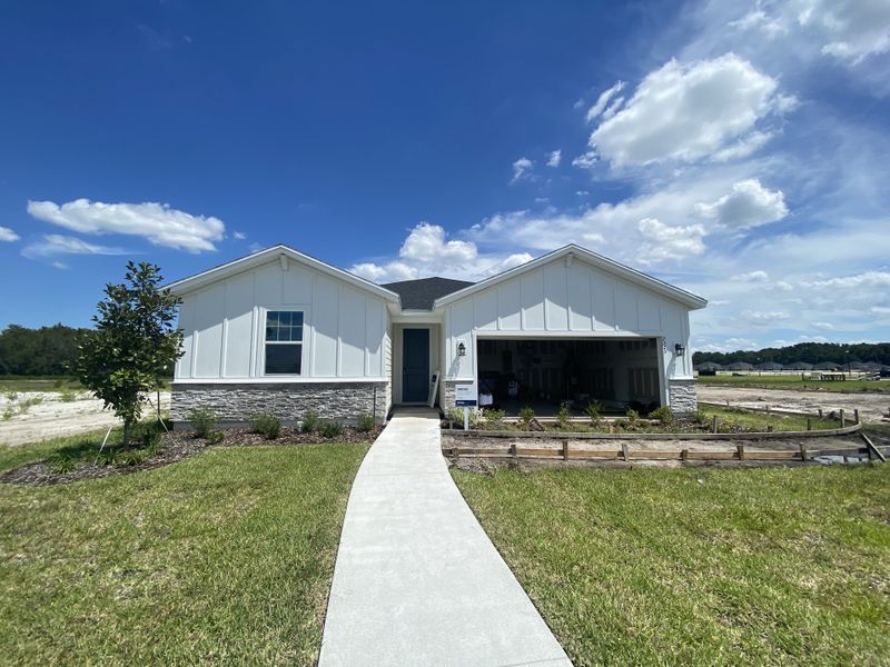 A modern white home with stone accents and a landscaped yard in Cypress Meadows - Signature Series by Meritage Homes (Jacksonville, FL).