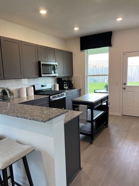 Modern kitchen with sleek gray cabinets, granite countertops, and stainless steel appliances, featuring a movable island.