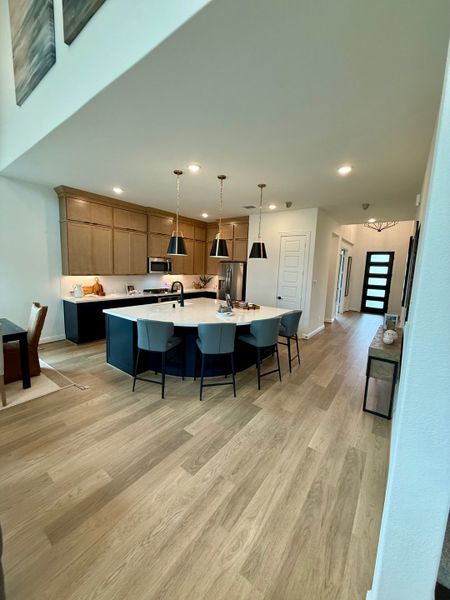 A modern kitchen with sleek wood flooring, pendant lighting, and a spacious island with seating. A modern kitchen with sleek wood flooring, pendant lighting, and a spacious island with seating.