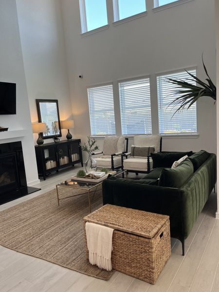A chic living room featuring high ceilings, dark green sofa, and large windows for ample natural light. A chic living room featuring high ceilings, dark green sofa, and large windows for ample natural light.