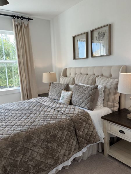 A cozy bedroom featuring a tufted headboard, layered bedding, and natural light from a large window. A cozy bedroom featuring a tufted headboard, layered bedding, and natural light from a large window.