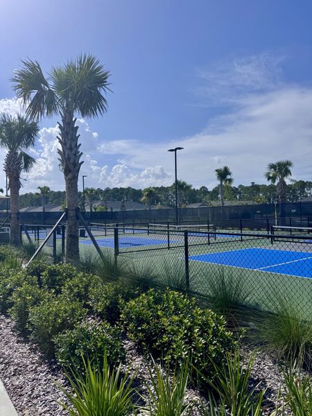 Tennis courts and lush landscaping under a bright blue sky in Edenbrooke at Hyland Trail by Lennar (Green Cove Springs, FL).