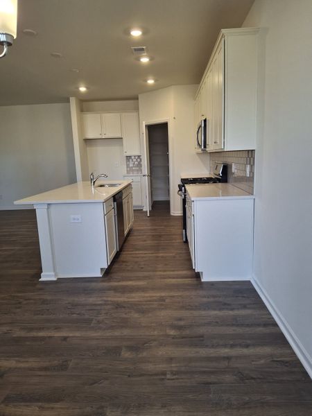 A modern kitchen with sleek white cabinetry, stainless steel appliances, and dark hardwood floors. A modern kitchen with sleek white cabinetry, stainless steel appliances, and dark hardwood floors.