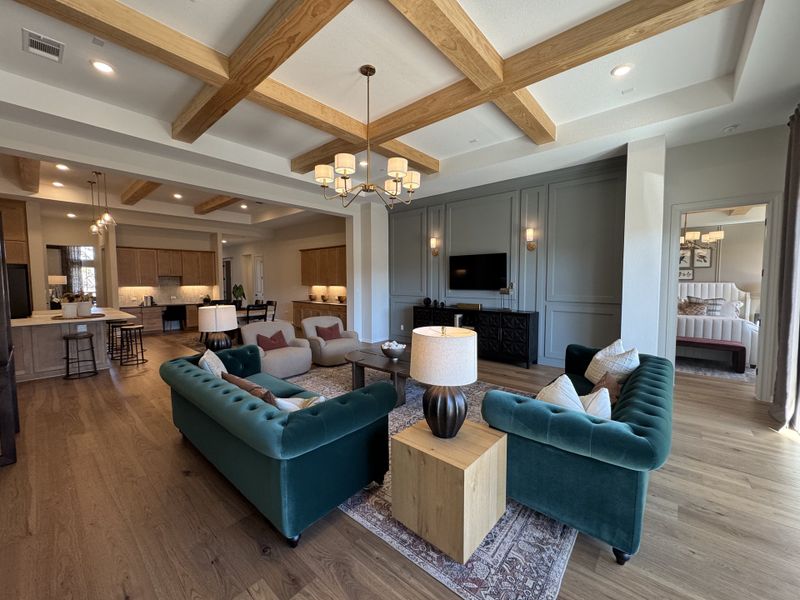 An elegant open-concept living area with plush teal sofas, exposed wood beams, and ambient lighting.