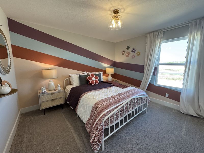 A cozy bedroom with striped accent wall, decorative pillows, and bedside lamps create a welcoming atmosphere.