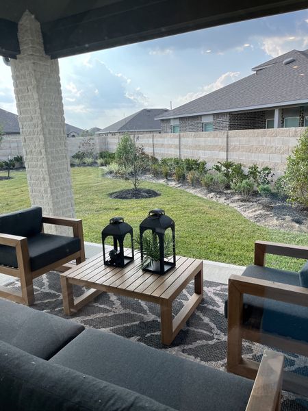 A cozy patio with modern furniture, decorative lanterns, and a view of a landscaped yard under a blue sky. A cozy patio with modern furniture, decorative lanterns, and a view of a landscaped yard under a blue sky.