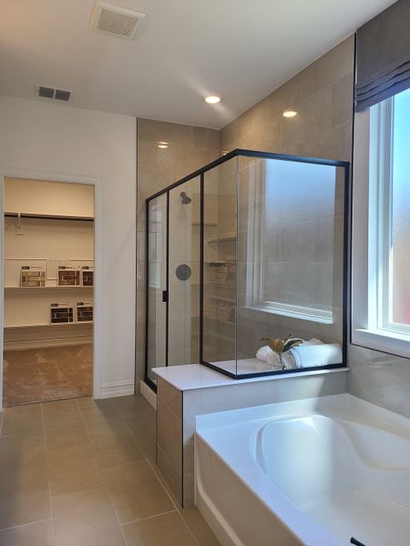 Sleek bathroom with a glass shower, spacious tub, and neutral tiles, leading to a walk-in closet. Sleek bathroom with a glass shower, spacious tub, and neutral tiles, leading to a walk-in closet.