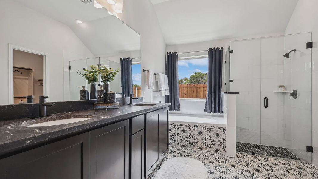 Indulge in elegance with a black marble vanity, intricate patterned tiles, and glass shower in Churchill Community. Indulge in elegance with a black marble vanity, intricate patterned tiles, and glass shower in Churchill Community.