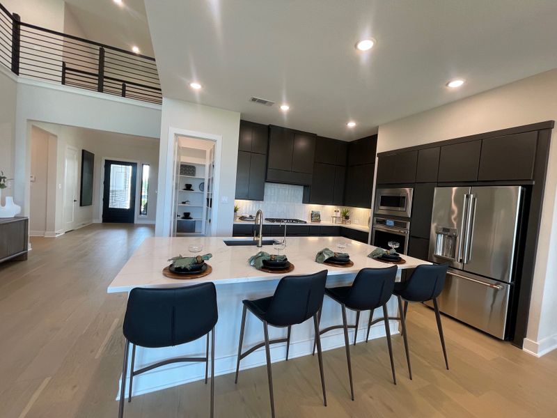 A modern kitchen with dark cabinets, stainless steel appliances, and an island with seating. Open layout and stylish lighting. A modern kitchen with dark cabinets, stainless steel appliances, and an island with seating. Open layout and stylish lighting.