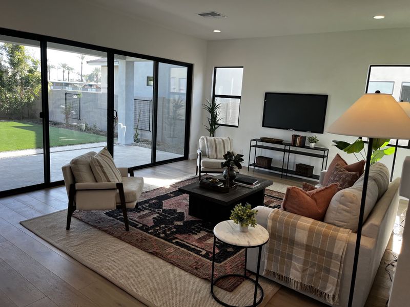 A contemporary living room featuring a cozy sofa, chic area rug, and large glass doors opening to a landscaped yard. A contemporary living room featuring a cozy sofa, chic area rug, and large glass doors opening to a landscaped yard.