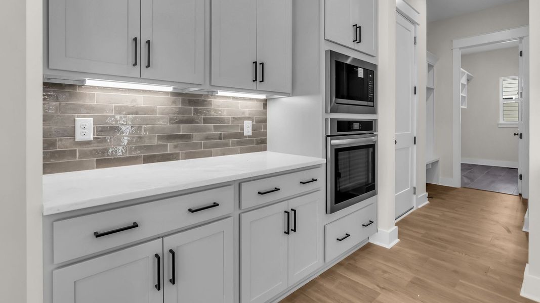 Kitchen with spacious grey cabinetry, sleek tile backsplash, and light quartz countertops Kitchen with spacious grey cabinetry, sleek tile backsplash, and light quartz countertops