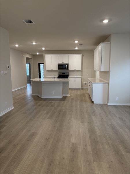 A modern kitchen with spacious layout, wood flooring, and white cabinetry. Perfect for entertaining and family gatherings.