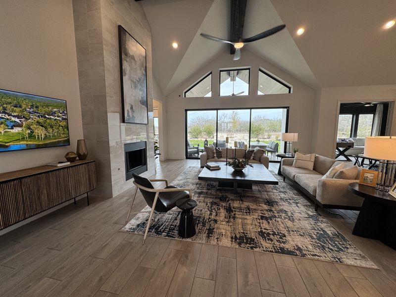 Spacious living area with high ceilings, modern décor, cozy fireplace, and expansive windows overlooking a serene view. Spacious living area with high ceilings, modern décor, cozy fireplace, and expansive windows overlooking a serene view.
