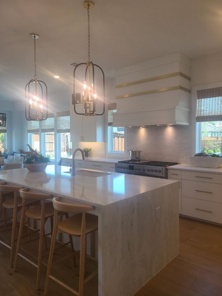 A modern kitchen with a sleek island, pendant lights, and natural wood accents. Perfect for gatherings and culinary inspiration.