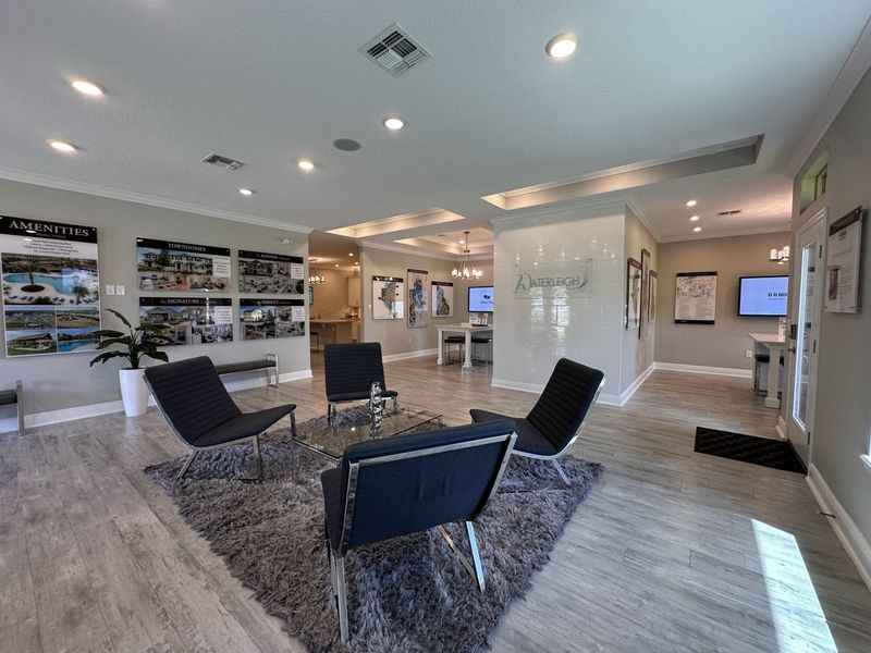 A modern sales office with sleek seating, informational displays, and stylish decor in neutral tones.