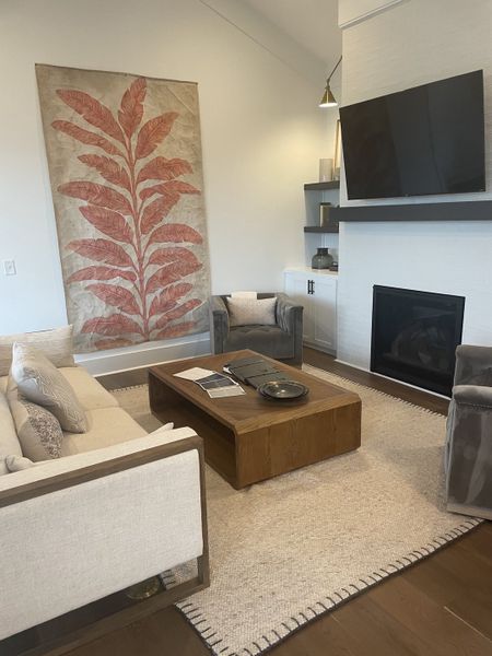 A cozy living room featuring a large botanical artwork, elegant seating, and a sleek modern fireplace. A cozy living room featuring a large botanical artwork, elegant seating, and a sleek modern fireplace.