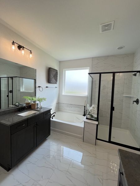 A modern bathroom with a sleek glass shower, elegant tub, dark vanity, and chic lighting. A modern bathroom with a sleek glass shower, elegant tub, dark vanity, and chic lighting.