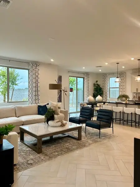 A modern living area with a neutral palette, spacious seating, and elegant decor connected to an open kitchen.