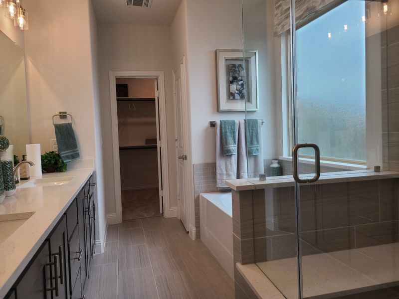 A modern bathroom featuring a sleek double vanity, spacious glass shower, and a bright, inviting bathtub area.