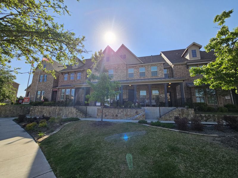 A charming brick townhome with lush greenery in Bayside by Beazer Homes (Rowlett, TX).