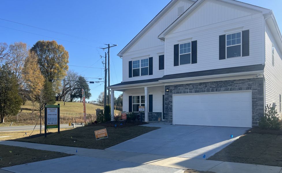 A charming white two-story home with stone accents and a neat driveway in Orchard Creek by Smith Douglas Homes (Charlotte, NC).