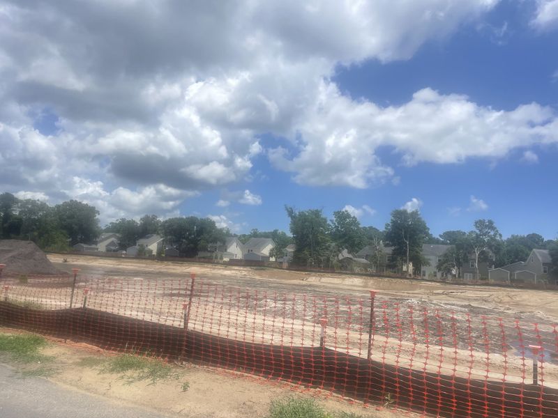 Future homesite under bright skies with houses nearby in Miller's Crossing by Dream Finders Homes (Johns Island, SC).
