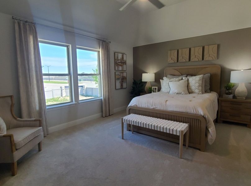 A serene bedroom with large windows, elegant decor, neutral tones, and cozy seating, creating a restful retreat.