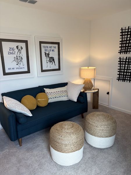 A cozy living area with a navy sofa, playful dog art, round poufs, and warm lighting, creating a welcoming ambiance.