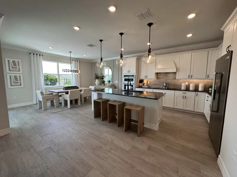 A spacious kitchen and dining area with modern lighting, a large island, and sleek cabinetry.