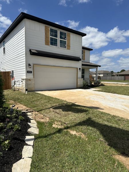 Modern white home with wood accents and a neat yard in Willow Trace 45' by Century Communities (Spring, TX).
